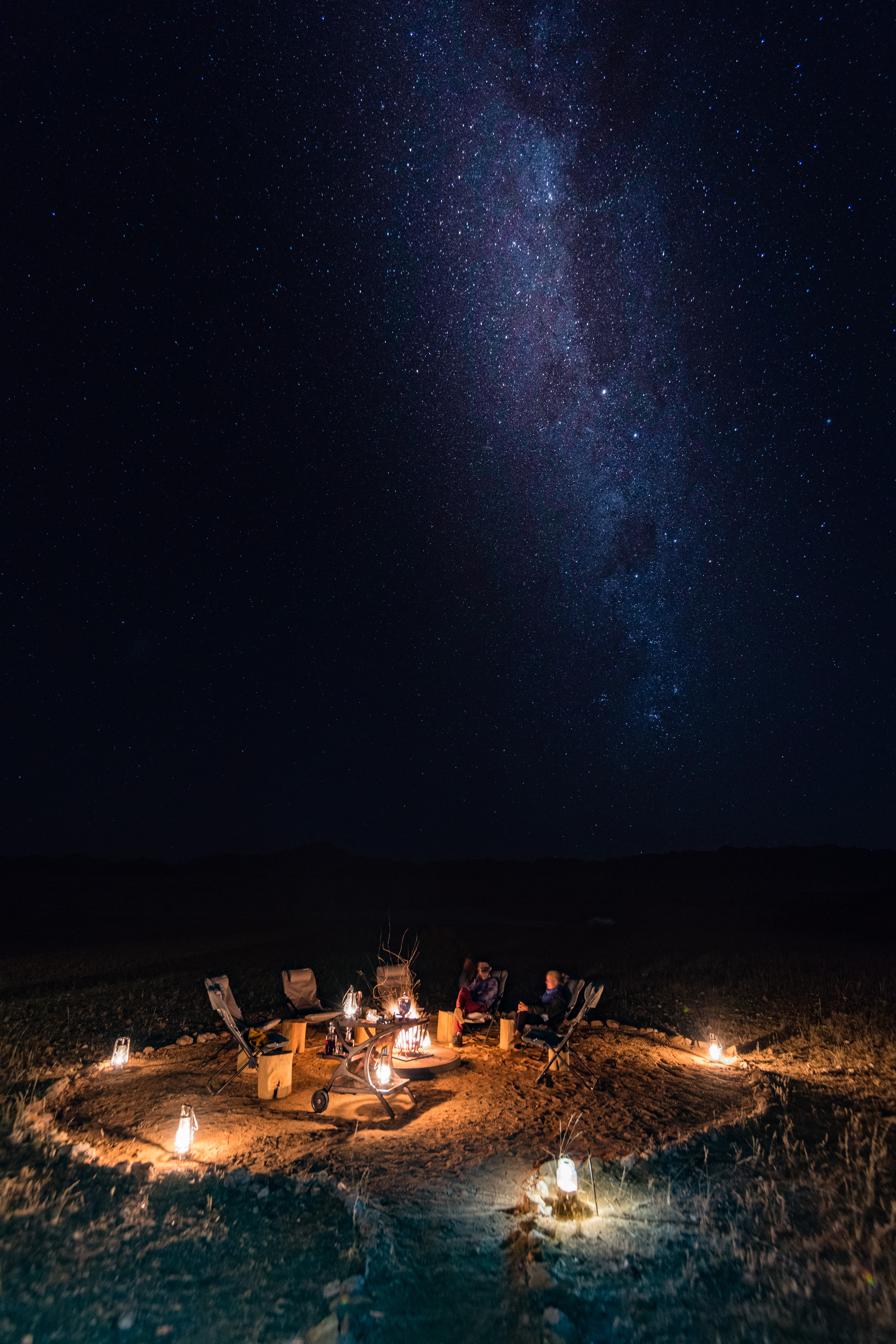 Guests around a campfire under the Milky Way, Namibia